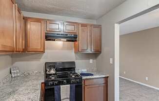 an empty kitchen with wood cabinets and a black stove