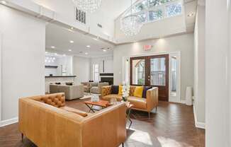 A living room with a brown couch and a chandelier.