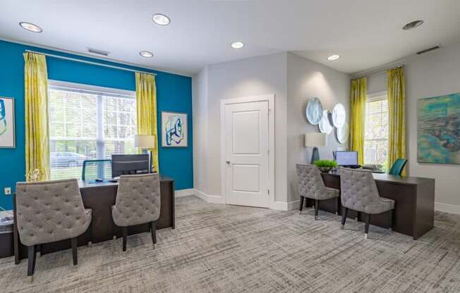 A room with two desks and chairs, one of which has a laptop on it.