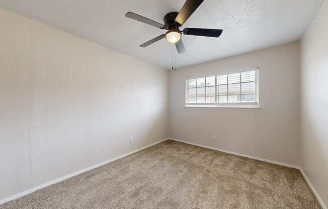 an empty room with a ceiling fan and a window