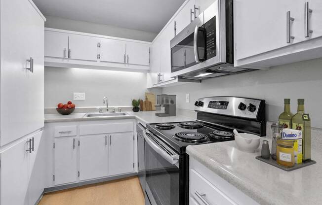 a kitchen with white cabinets and a stove and microwave