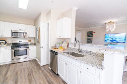 a kitchen with white cabinets and granite counter tops and stainless steel appliances