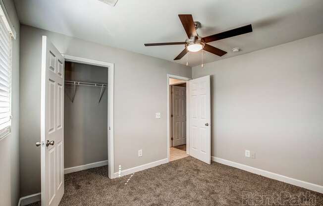 a bedroom with a ceiling fan and closet