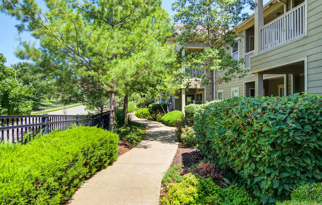 A walkway leads through a landscaped area between two apartment buildings.