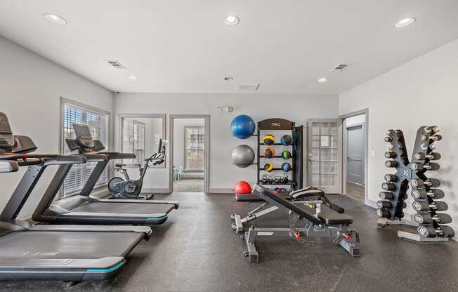 A spacious home gym with treadmills, exercise balls, and dumbbells.