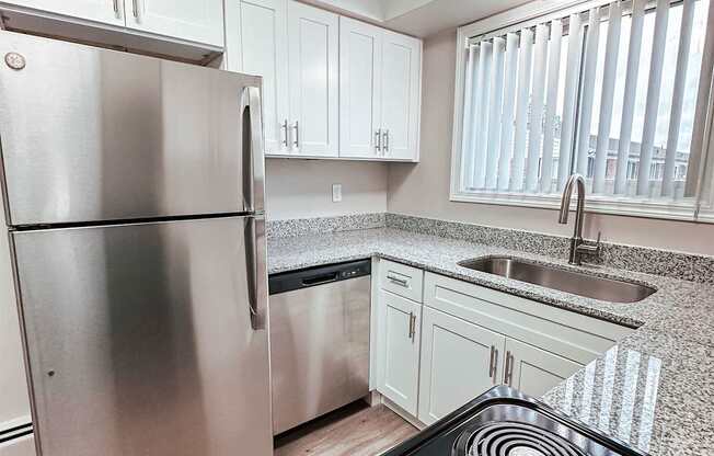 A modern kitchen with a stainless steel refrigerator and black stove top.
