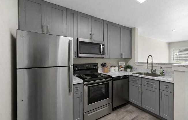 A modern kitchen with stainless steel appliances and grey cabinets.