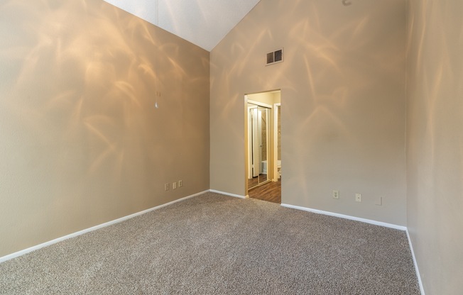 A room with a carpeted floor and a doorway leading to another room.