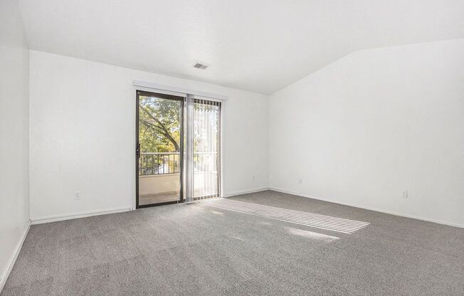living room with a cathedral ceiling and sliding glass door to a balcony at Hampton Lakes Apartments, Michigan, 49534