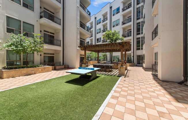 a courtyard with a picnic table and a ping pong table in an apartment building