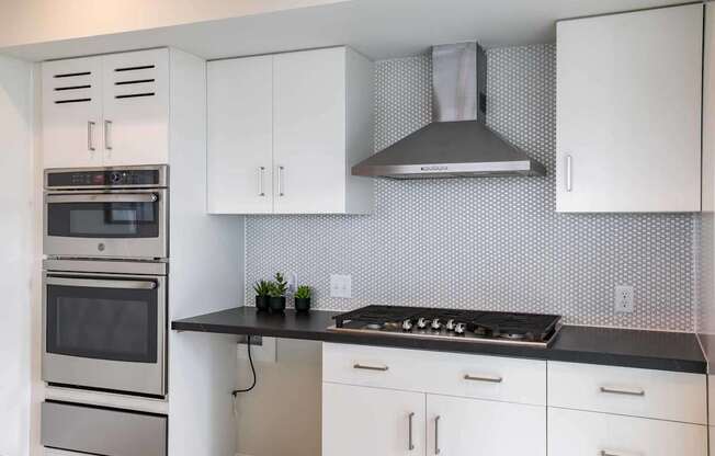 A modern kitchen with white cabinets and a black countertop.