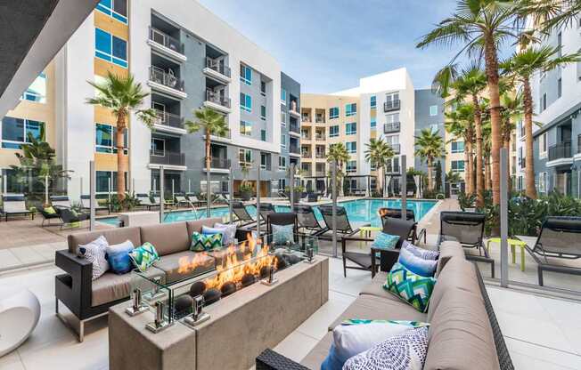 A modern outdoor seating area with a fire pit in the middle.
