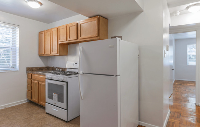 A kitchen with a white refrigerator and wooden cabinets.