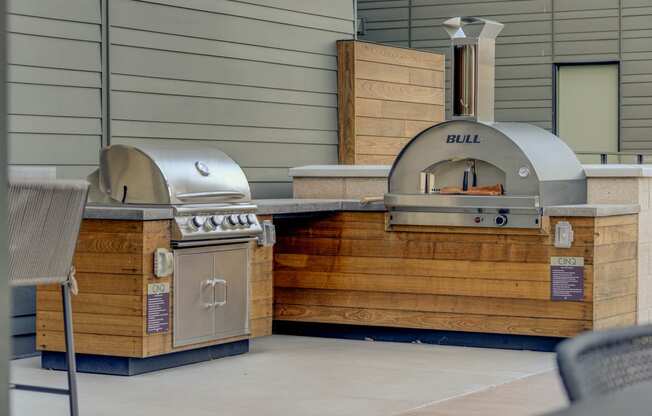 a bbq area with two stainless steel grills and a wooden grill