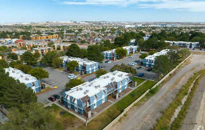 A view of a residential area with apartment buildings and cars parked in the driveways.