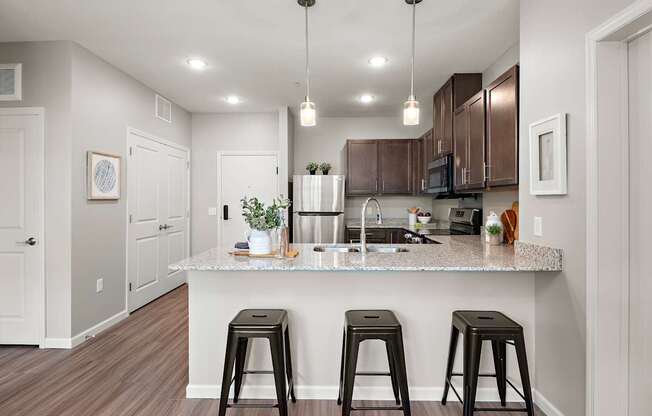 A kitchen with a granite countertop and bar stools.