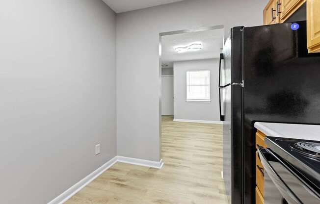 a kitchen with a refrigerator and a stove and a hallway with a door to a