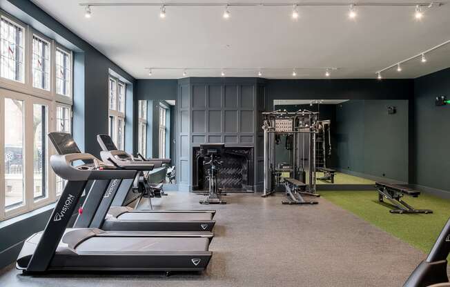 a gym with treadmills and other exercise equipment and a fireplace