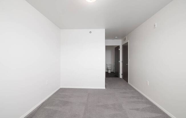 A large empty room with a carpeted floor and white walls.