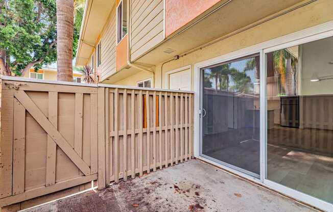 A wooden fence is in front of a tan house.
