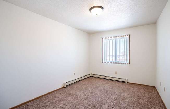 A room with a window and a carpeted floor.