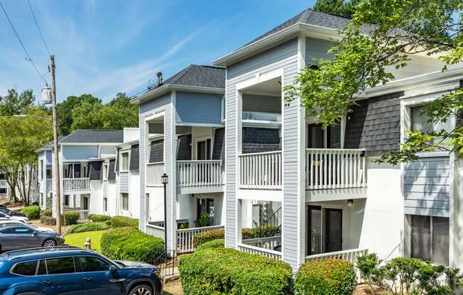 a row of white houses with cars parked in front of them