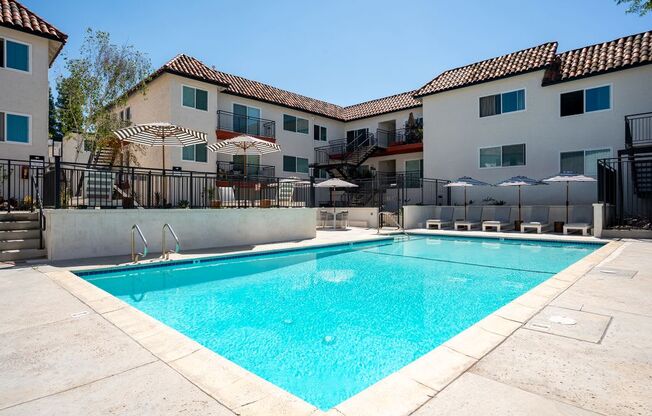 A swimming pool in front of a building with a black fence around it.