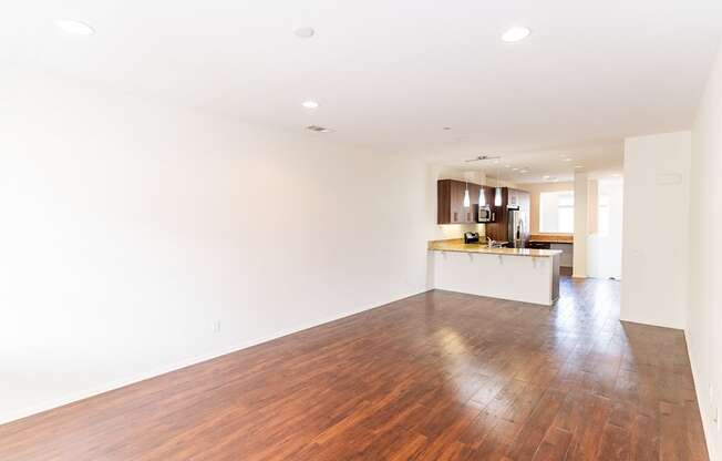 an empty living room and kitchen with wood floors and white walls at The Vines at Riverpark, LLC, California, 93036