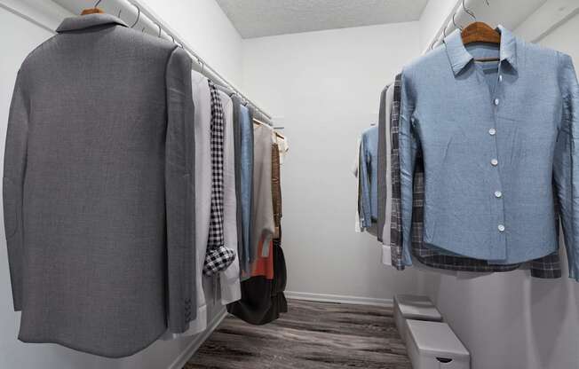 a closet with shirts and jackets hanging on the wall