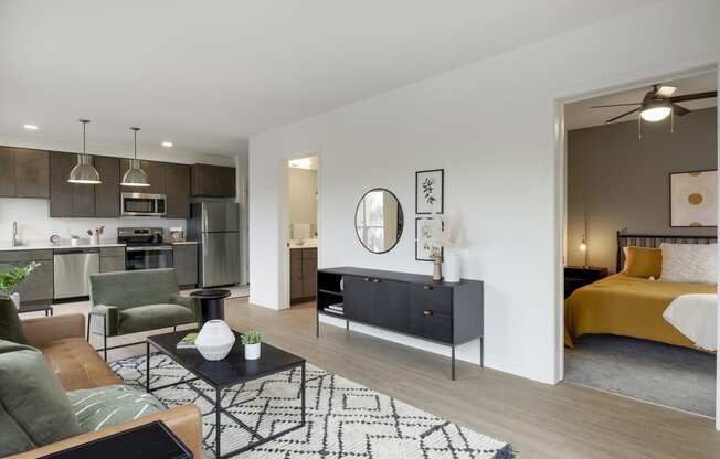 a spacious living room with a kitchenette and bedroom in the background