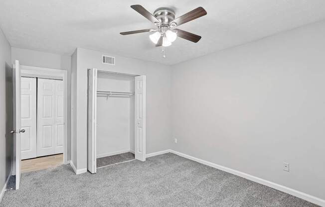 A room with a ceiling fan and a carpeted floor.