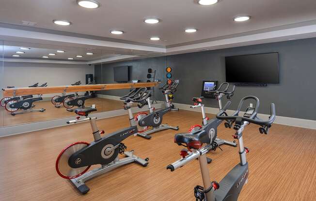 a gym with various exercise bikes and a television at The Tribute, Raleigh, NC