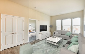 living area with sofa, coffee table, large windows, credenza, tv and view of bedroom at city view apartments in washington dc