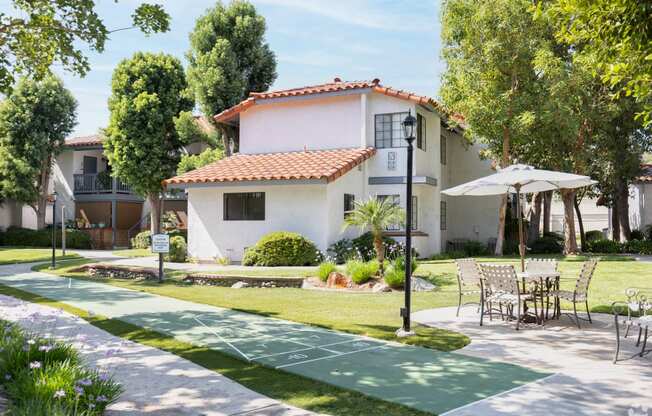 a path with chairs and tables on it in front of a house