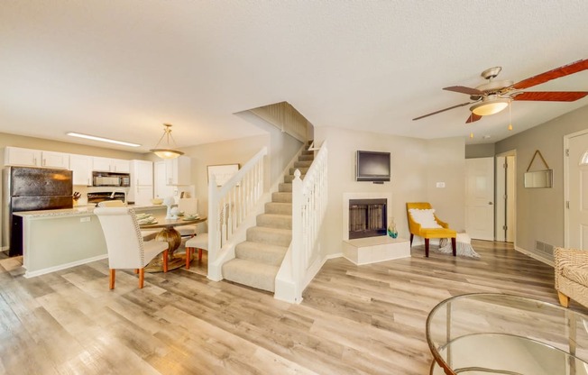 a living room with a staircase and a kitchen with a fireplace
