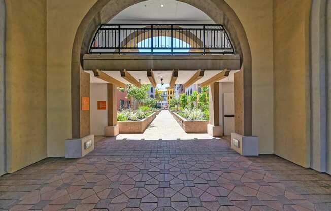 A courtyard with a brick floor and a balcony overlooking the plants.