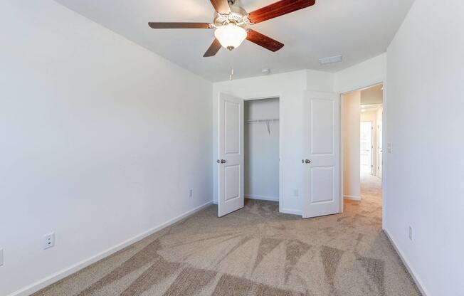 Three-Bedroom Townhomes in North Charleston, SC - Highland Townhomes - Carpeted Bedroom with White Walls, Ceiling Fan, and Large Closet.