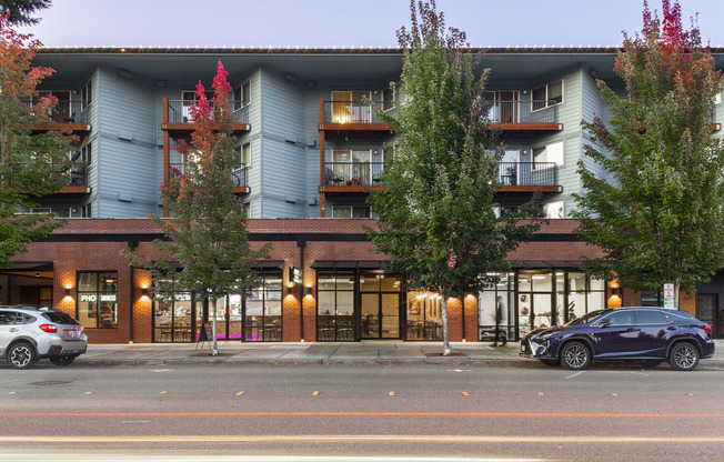 Building exterior at dusk with large green trees and balconies at 6 Wood Flats, Lacey Washington