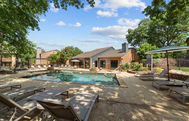 A pool surrounded by lounge chairs and trees.