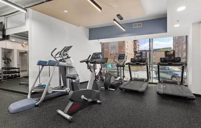 a gym with treadmills and other exercise equipment in a room with a window