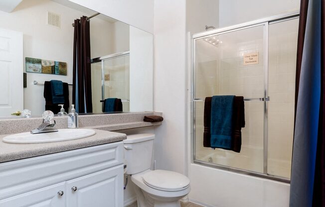 A white bathroom with a toilet, sink, and shower.