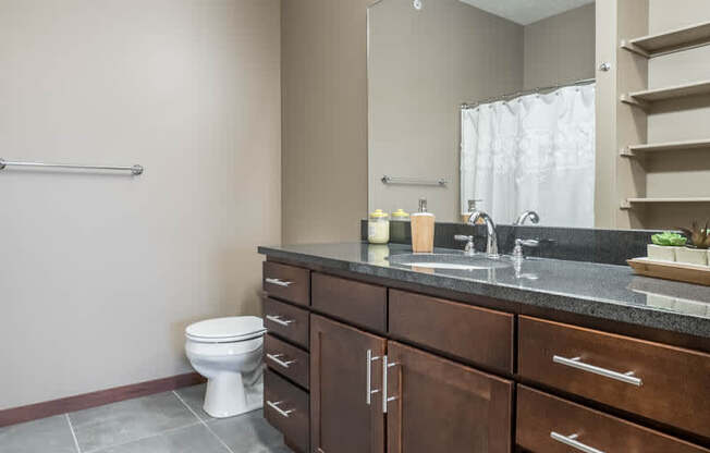 A bathroom with a toilet, sink, and mirror.