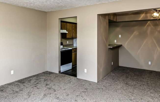 an empty living room with a door to a kitchen