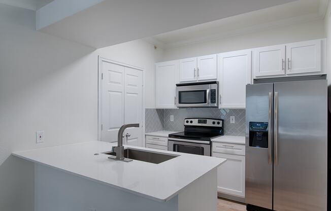 a kitchen with white cabinets and stainless steel appliances