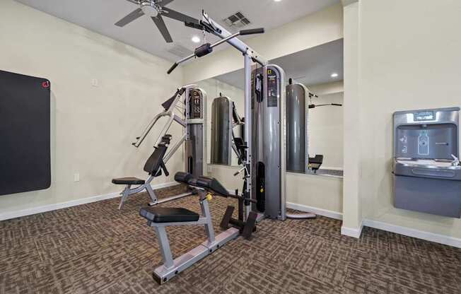 A home gym with a weight machine, a bench, and a fan.