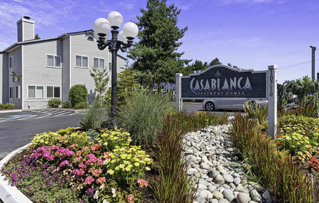 Casablanca Property Sign with flowers, bushes, and stone path in front at Casa Blanca Apartment Homes, Washington