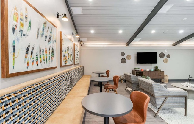 A room with a table, chairs and a wall of art.