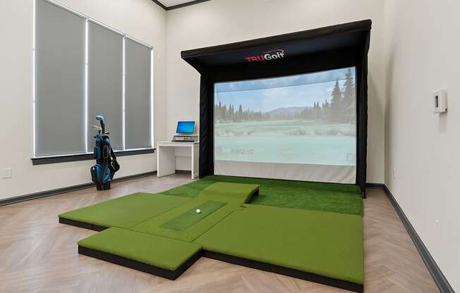 A room with a golf simulator and a golf bag.