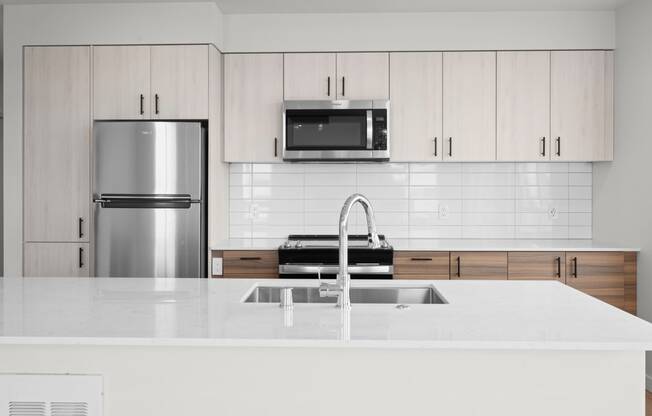 a kitchen with white countertops and white cabinets with a stainless steel refrigerator and microwave at Ion Town Center, Washington