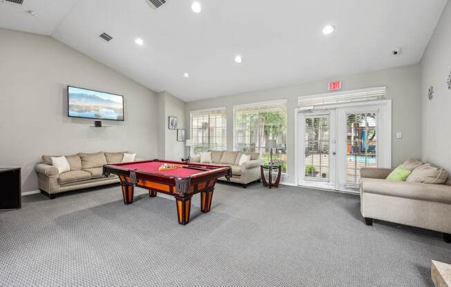 A room with a pool table and a television.